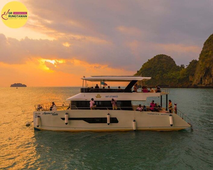 Ein Boot mit Personen, umgeben von Wasser und Klippen bei Sonnenuntergang. 2