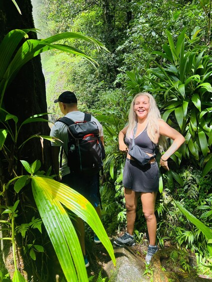 Two people hiking in a dense forest with lush green foliage. 3