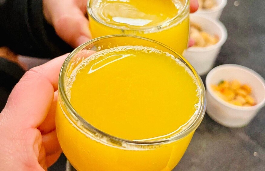 Two glasses of orange juice being held by a person. 3
