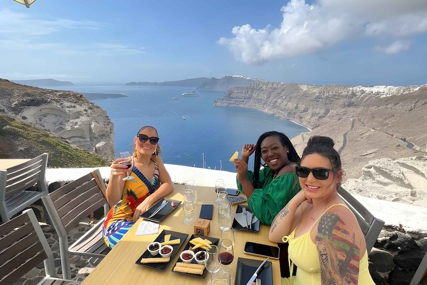 Three people dining at a table with a scenic view of a coastal landscape. 4