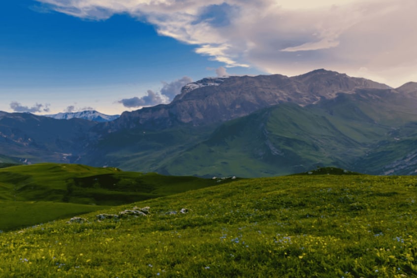 Un paisaje montañoso con colinas verdes y cielo despejado. 4