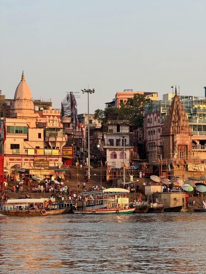 A riverside cityscape with a prominent temple, boats, and a busy waterfront. 3