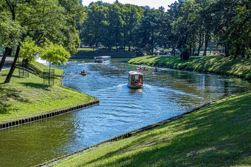 A river with boats, a wooden boat in the center, and a grassy bank. 3
