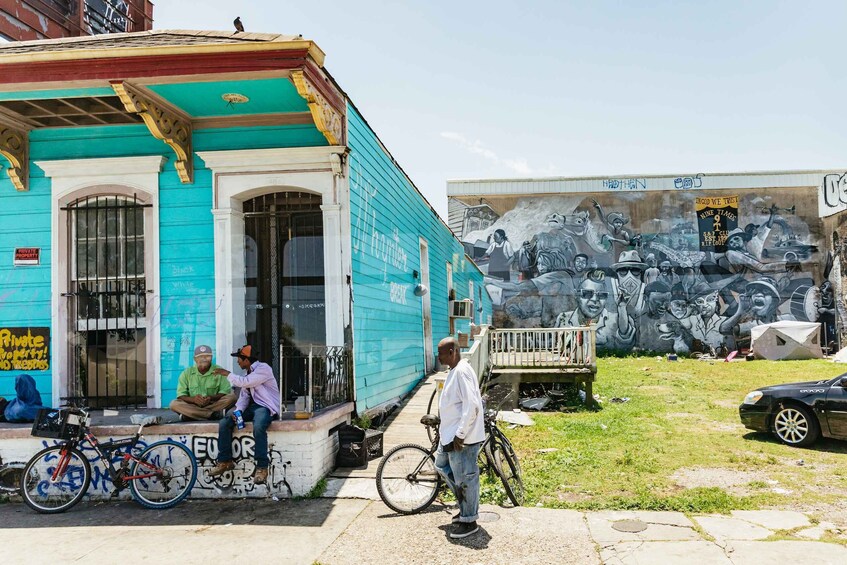 A turquoise building with graffiti and a mural on the side. 1