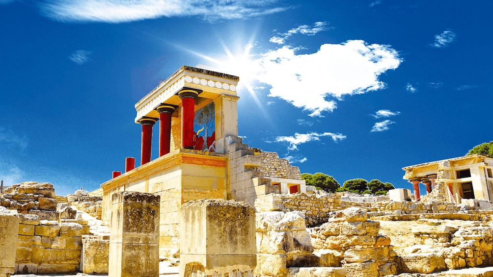 Ancient ruins with columns and a temple structure under a clear blue sky. 1