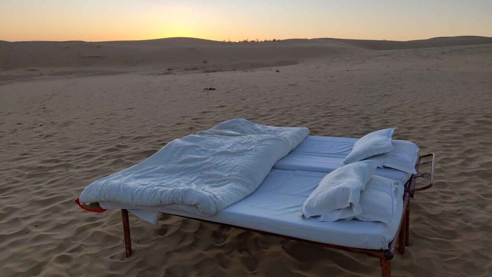 A bed in a desert at sunset. 5