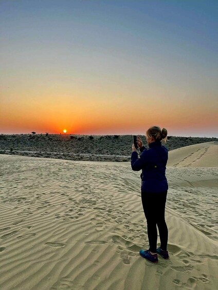 A person taking a photo of the sunset over a desert landscape. 5
