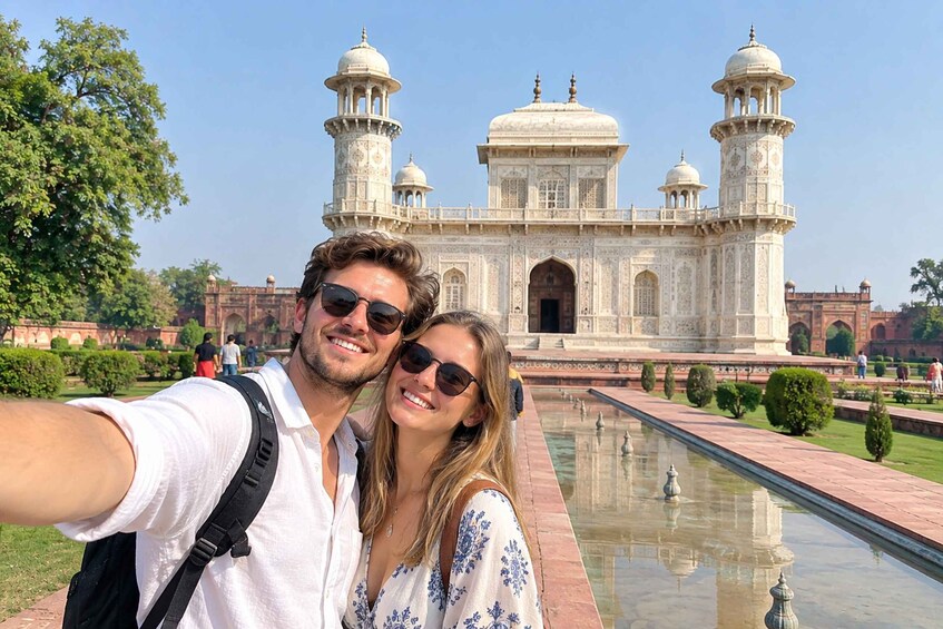 A couple taking a selfie in front of the Taj Mahal with its reflection in the water. 3