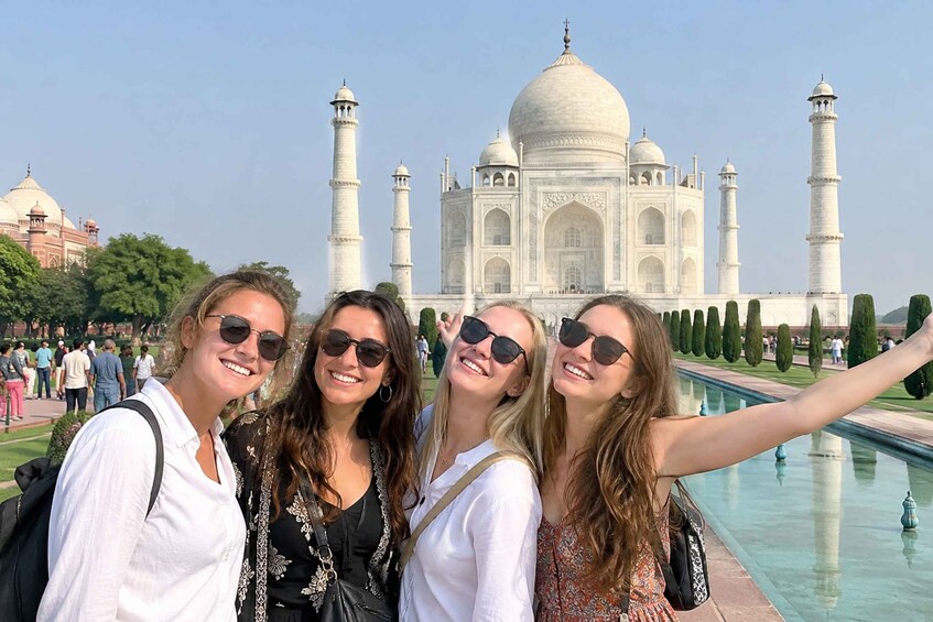 Four people taking a selfie with the Taj Mahal in the background. 1