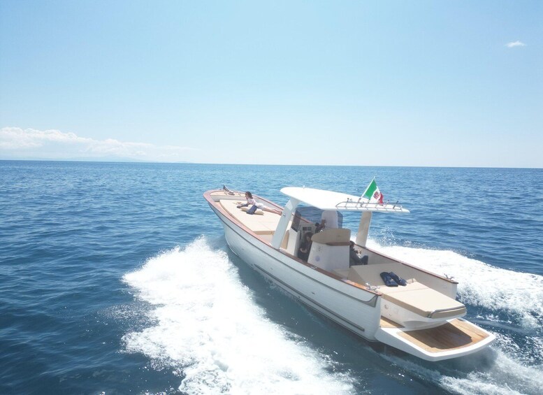 A speedboat with a flag, moving through calm blue waters under a clear sky. 2