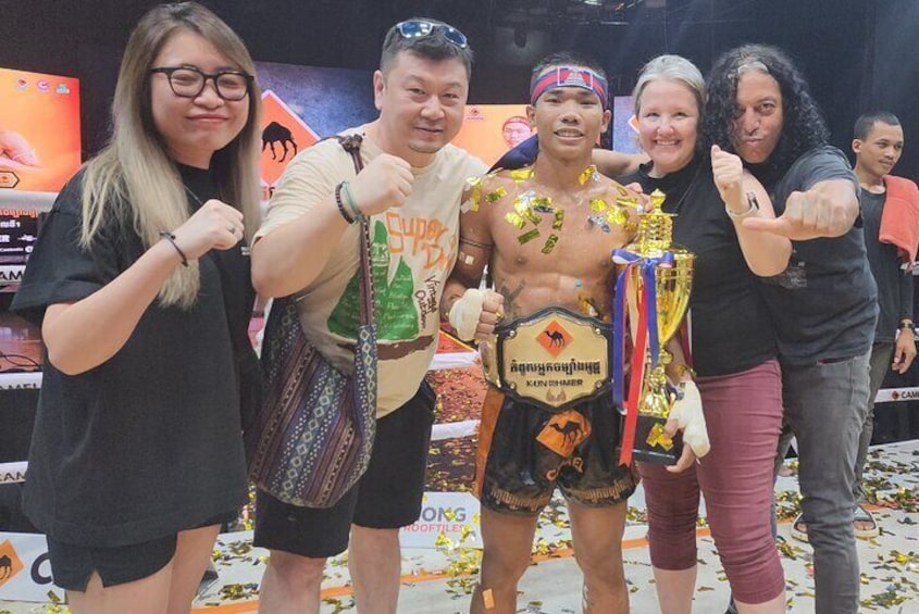A person holding a trophy, surrounded by others. 1
