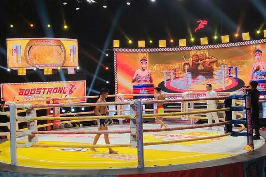 A boxing ring with a large promotional banner in the background. 3