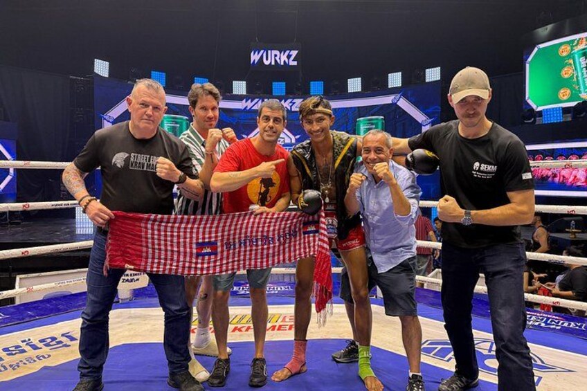 A boxing ring with a checkered cloth, a man in a red shirt, and another in a black shirt. 2