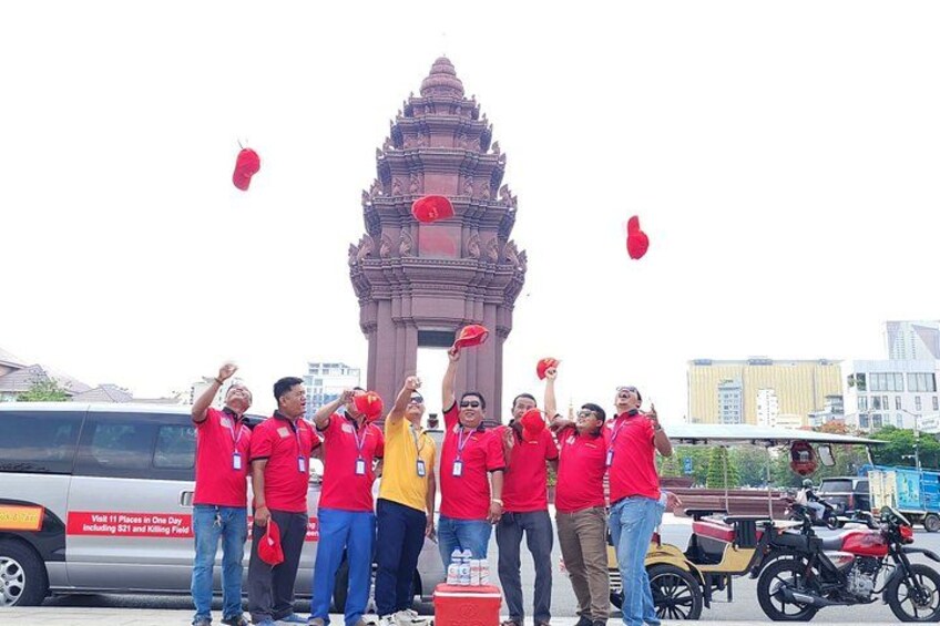 Un grupo de personas con camisetas rojas frente a un templo, con una camioneta y motocicletas al fondo. 3