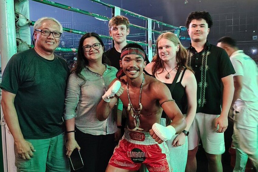 A group of people in a gymnasium with boxing equipment and a boxing ring. 5