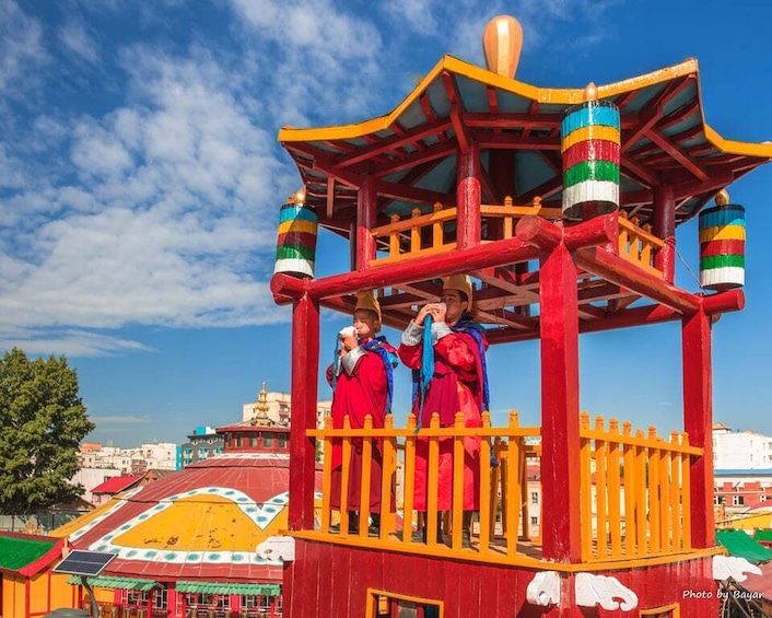 A colorful pavilion with a striped roof, surrounded by a yellow fence. 2