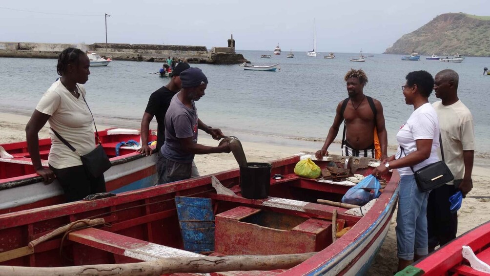 A group of people on a beach with several small boats. 1