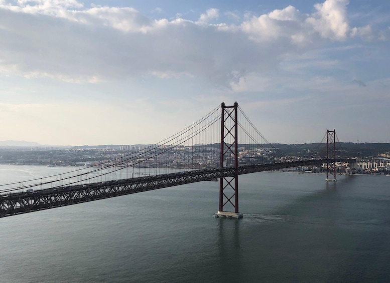 Eine lange Hängebrücke überspannt einen breiten Fluss, im Hintergrund ist eine Stadtlandschaft zu sehen. 5