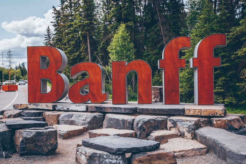 Large wooden letters spelling "Banff" on a rocky base with a forested background. 2