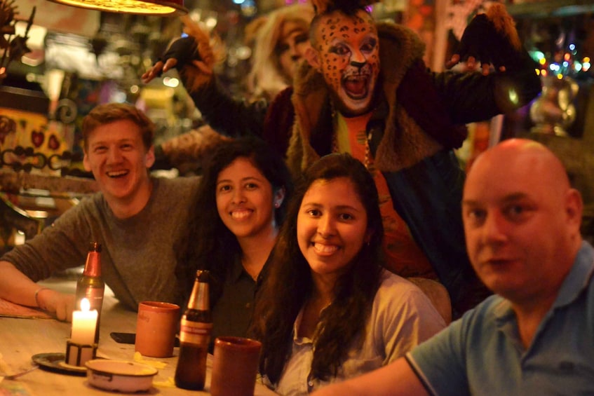 A group of people at a table with a candle, bottles, and a leopard mascot. 1