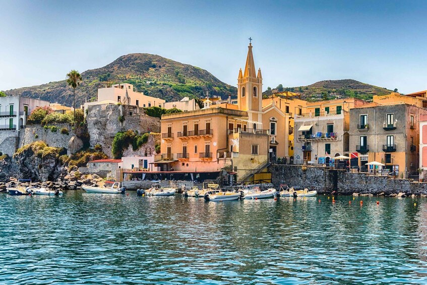A coastal town with historic buildings, a church, and boats docked at the harbor. 1