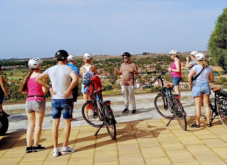 Un gruppo di persone con biciclette su una superficie pavimentata con vista su un paesaggio suggestivo. 5