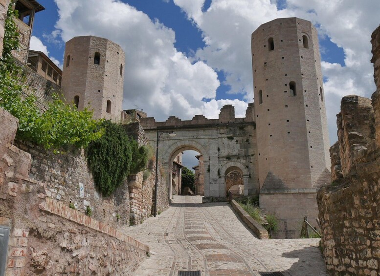 An ancient stone archway leading to a fortified gate with two towers. 1