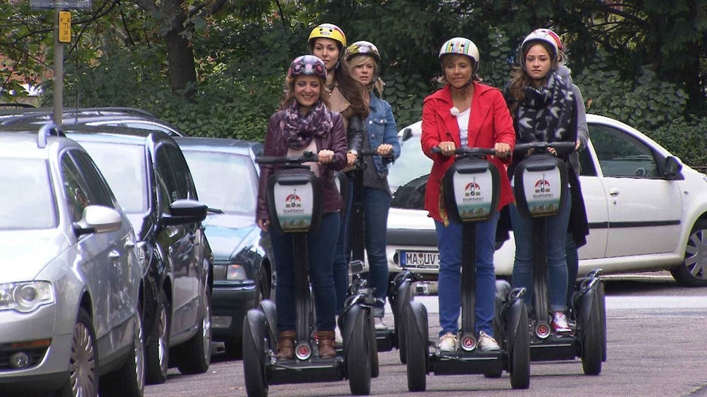 A group of people on Segways in a parking lot with cars. 3