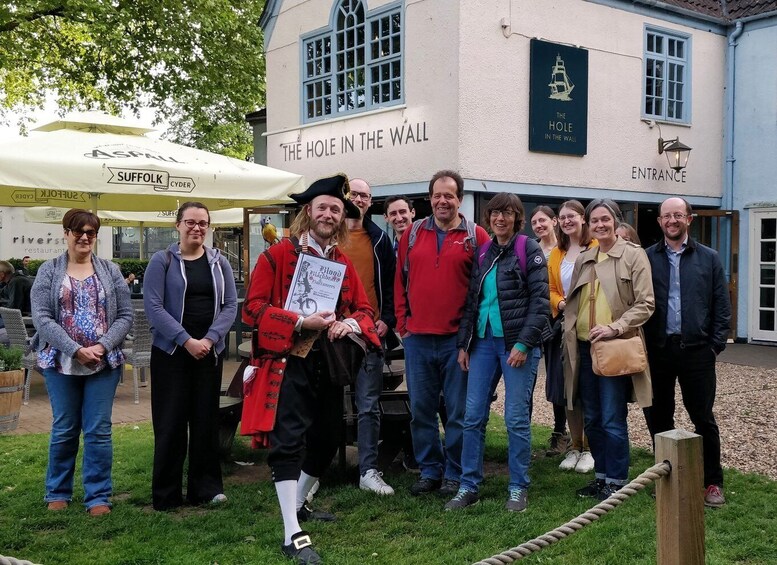 A group of people standing in front of a building with a sign that reads 'THE HOLE IN THE WALL.' 2