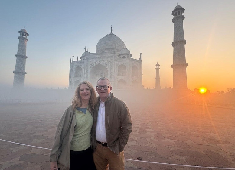 Pariskunta seisoo Taj Mahalin edessä, ja taustalla auringonlasku värjää taivaan. 1