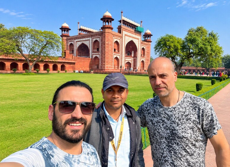 Three people taking a selfie in front of a large, historic building with domes and arches. 3