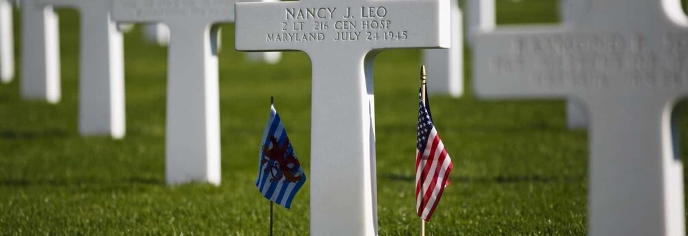 A white gravestone with a flag and an American flag. 2