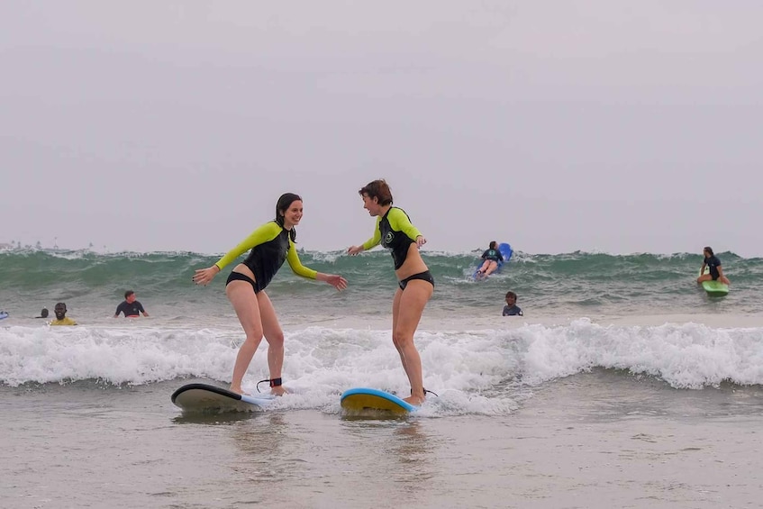 Two people surfing on a beach with waves. 1