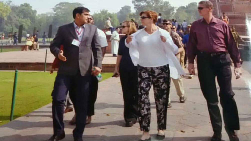 People walking in a park with a fountain and trees in the background. 5