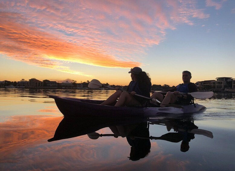 Two people in a boat on a calm body of water during sunset. 4