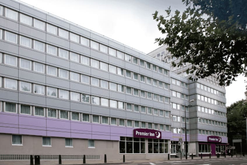 A multi-story building with a purple facade and signage for Premier Inn. 3
