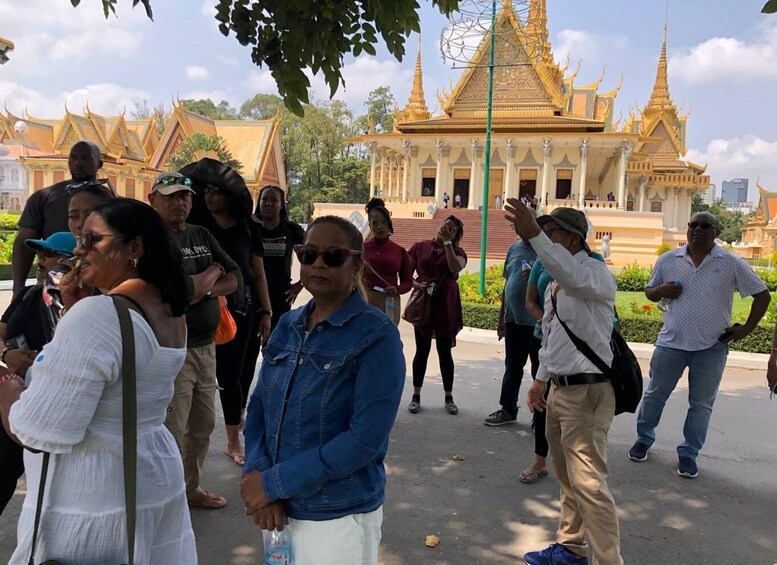 En gruppe turister foran et gyldent tempel med detaljeret arkitektur. 4
