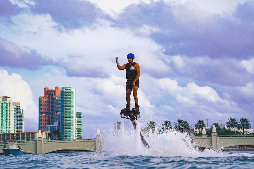 A person riding a jet ski over water with a cityscape in the background. 3