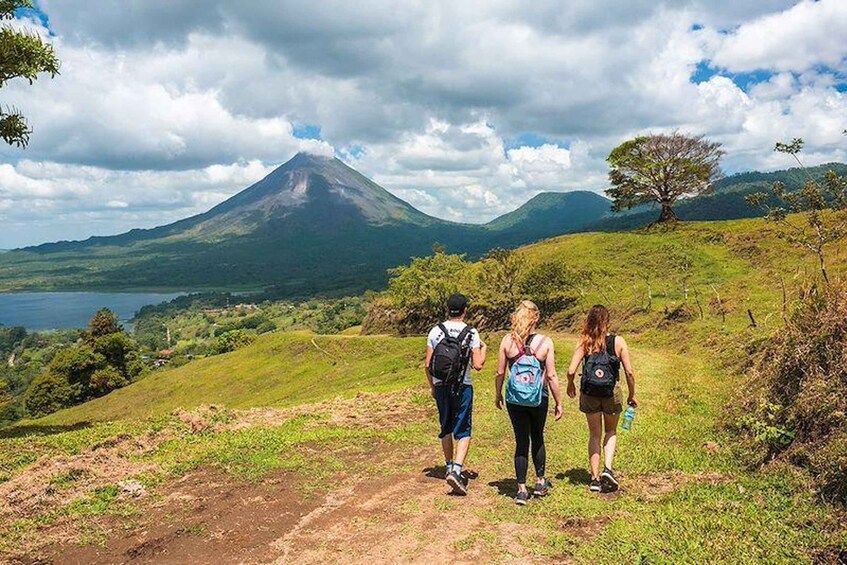 Three hikers on a trail with a volcano in the background. 5
