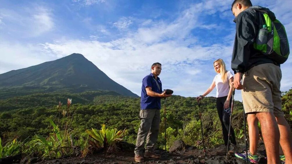 A group of people hiking with a volcano in the background. 2