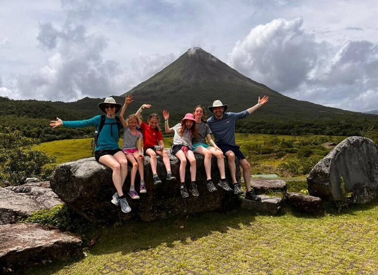 A group of people sitting on rocks with a mountain in the background. 1