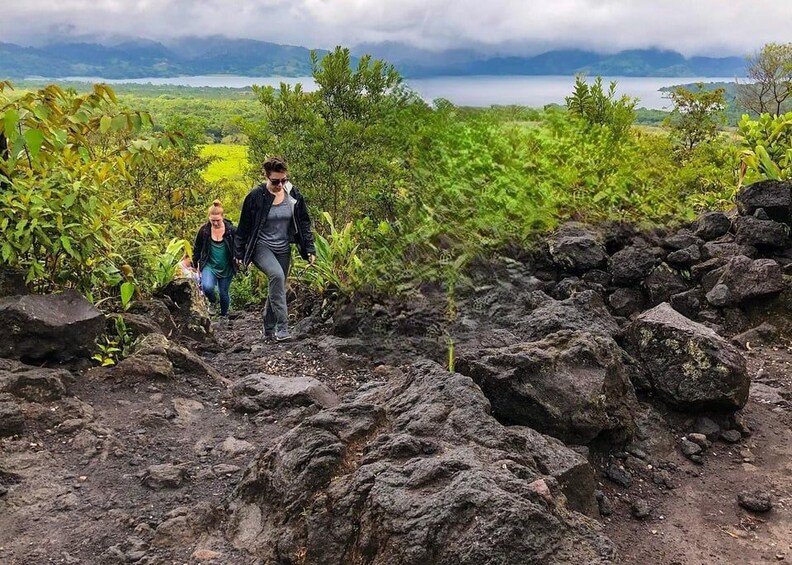 Deux personnes font de la randonnée sur un sentier rocailleux, avec un lac et des montagnes en arrière-plan. 3