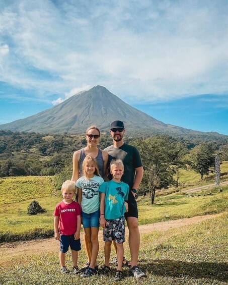 A family standing in front of a volcano with a clear sky. 3