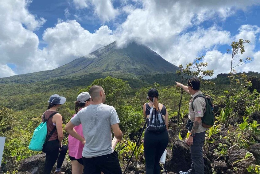 A group of people hiking near a volcano with a cloudy sky. 4