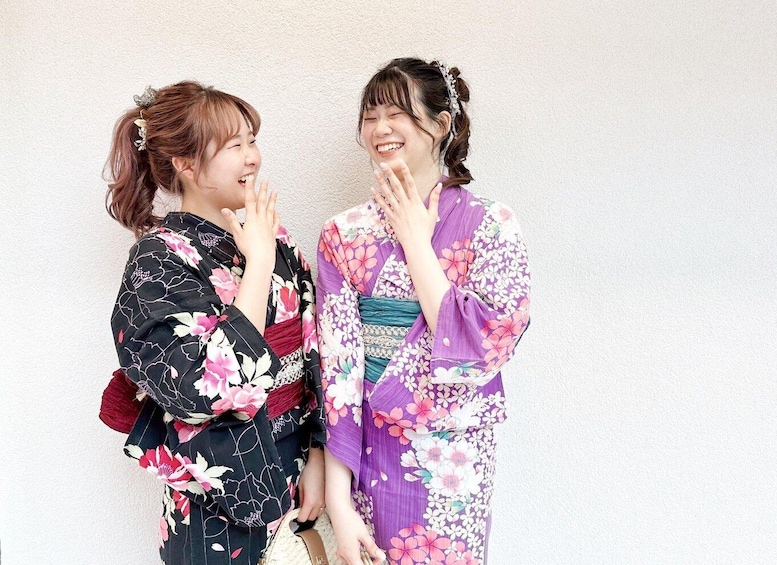 Two individuals in traditional Japanese kimonos standing against a plain wall. 5