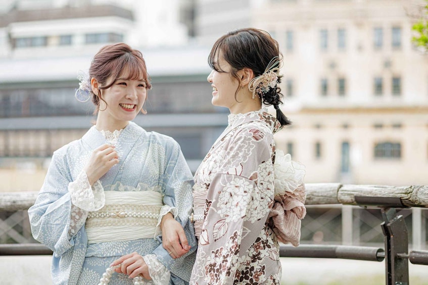 Two individuals in traditional attire, holding hands, with a modern building in the background. 2