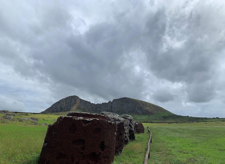 A large rock formation in a grassy field with a cloudy sky. 4