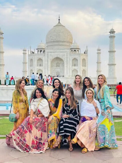 A group of people in traditional attire posing in front of the Taj Mahal. 4