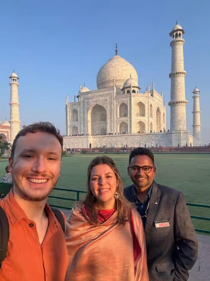 Three people standing in front of the Taj Mahal. 5