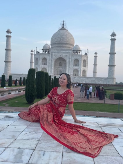 A person sitting on a tiled area in front of the Taj Mahal. 5